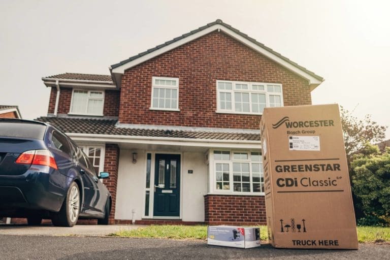 A house with a car parked in front with a Worcester Boiler delivered.