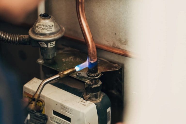 A man is servicing a water heater.
