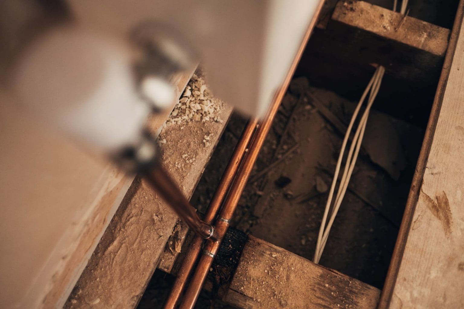 A Heatmyhohm plumber is performing maintenance on a central heating pipe in a room.