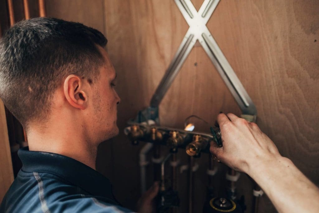 A Heatmyhohm plumber fixing a pipe in a home bathroom.